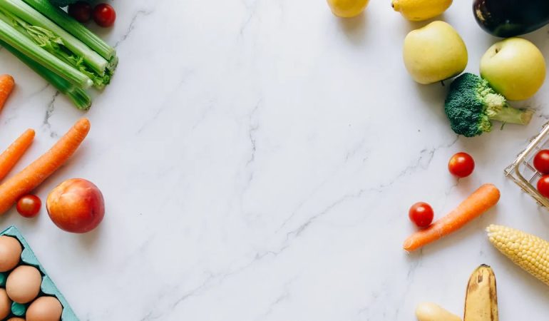 An assortment of fresh fruits and vegetables on a marble background, perfect for healthy lifestyle concepts.